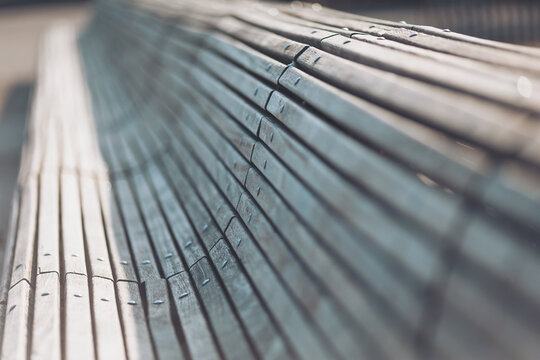 Wooden bench with smooth lines and water droplets glistening in sunlight at a park in the early morning