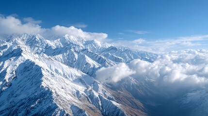 Breathtaking aerial view of snow-capped mountains under a clear blue sky with fluffy clouds. Nature's beauty at its finest.