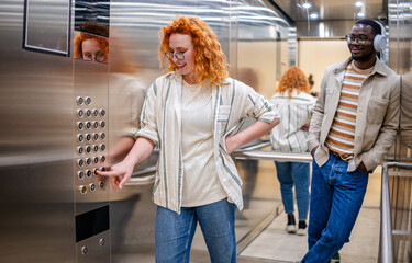 Ginger woman enjoys an elevator ride with black man while selecting a floor in the city building