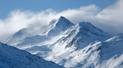 Majestic snow-capped mountains rise against a clear blue sky, enveloped in wispy clouds creating a serene winter landscape.