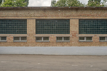 Old industrial brick building with large glass block windows and barred vents.