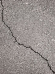 Jagged diagonal crack across rough gray concrete surface.