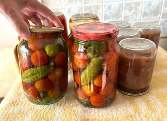 Hand Securing Jars of Homemade Pickles and Tomatoes