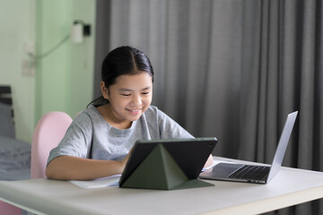 study online class by asian child smile learning on computer tablet or kid girl student fun studying or young woman people learn from home school by laptop to video call technology education in room