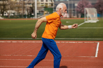 Side view of senior sportsman running fast on stadium.