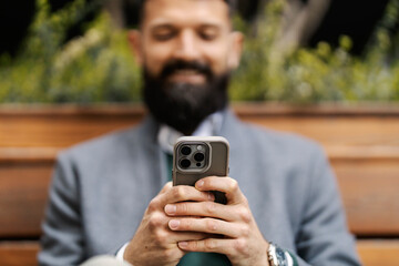Close up of an executive's hands typing online messages on a city street.