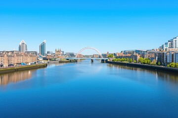 Obraz premium Summer river panoramic cityscape with iconic bridges, buildings, calm waters reflecting blue sky
