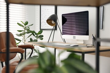 Stylish workplace with wooden desk, lamp and computer indoors