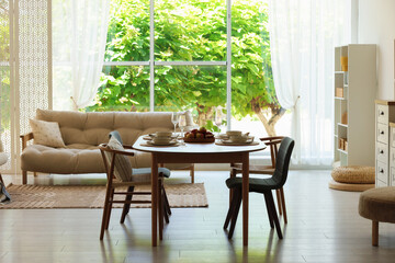 Beautiful table setting, chairs and decor in dining room. Interior design
