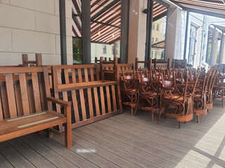 Closed cafe with wooden chairs and benches stacked on the terrace