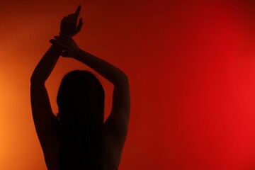 Silhouette of woman posing on red gradient background, back view. Space for text