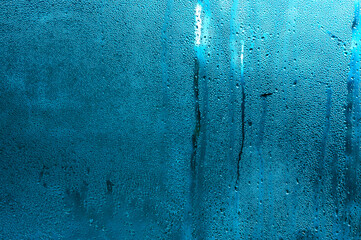 Condensation forms on cold glass, droplets run down glass. humid indoor atmosphere. shot of drops...