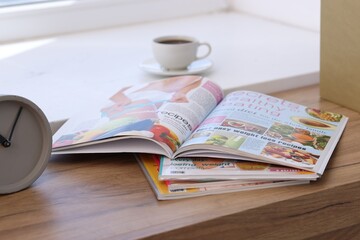 Lifestyle magazines on wooden table indoors, closeup