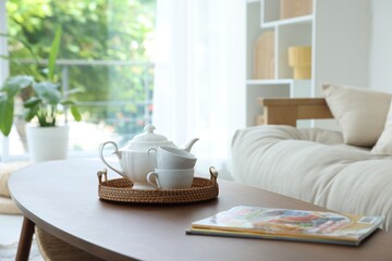 Teapot, cups and magazines on coffee table in dining room