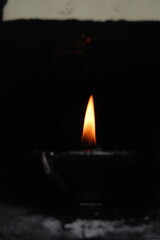 A single burning candle glowing warmly in the dark winter night, its flame a bright light against the cold snow