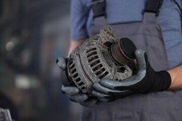 Auto part. Professional mechanic with alternator near indoors, closeup. Space for text