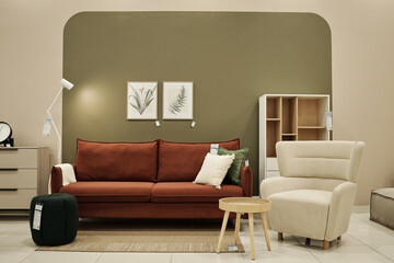 Modern furniture arrangement featuring brown sofa, beige armchair, small round table, green...