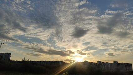 Cloudy landscape. Beautiful sunset, the silhouette of the city is visible on the horizon.