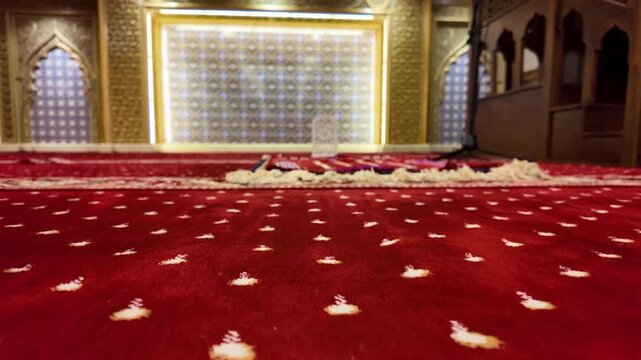 Slow motion panning of a serene mosque interior with red carpet and decorative details
