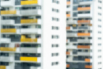 Out-of-focus blurred high-rise apartment buildings with white facades and yellow balcony accents....