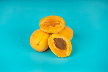 Juicy apricots with visible seed placed on vibrant blue background.