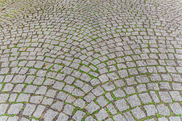 abstract background of stone tiled road in the park with grass in the joints close up top view