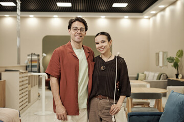 Young adult Caucasian man and young adult Caucasian woman standing together smiling in furniture...