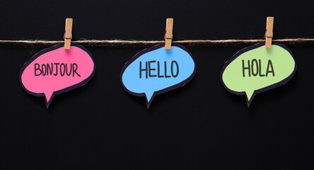 English school advertisement banner with three languages on speech bubbles hanging on the rope,...