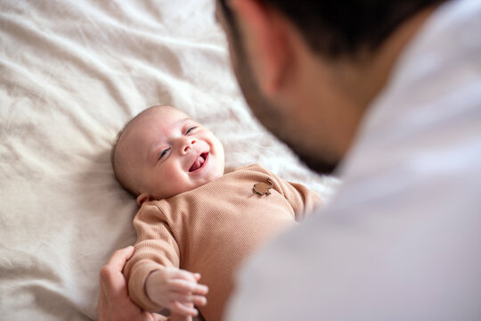 Photo of a cute newborn baby lying on his back in bed. Lifestyle, home.