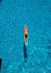Diver poised above sparkling blue water, preparing for a graceful springboard dive into the pool