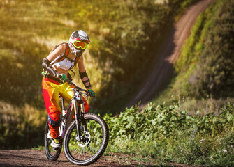 Extreme summer sports - young sportive strong woman or sportswoman riding downhill on mountain...