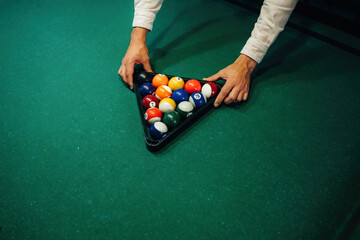 A man is placing billiard balls on a table