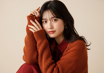 深まる秋のファッション、赤茶色のニットセーターとダークレッドのブラウスを着た女性ファッションモデル