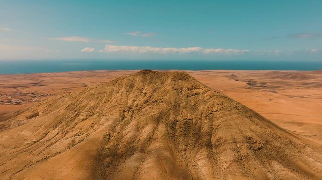 Aerial view of Mount Tindaya under midday sun with clouds casting shadows, Fuerteventura, Canary Islands