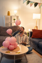 Man juggling pink balloons at home birthday party