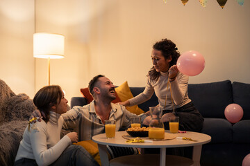 Family celebrating birthday at home with balloons and snacks
