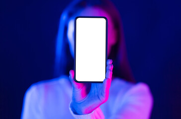 Mockup. Woman showing blank smartphone screen in studio with blue and pink neon lights, free space