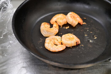 Sizzling frying pan with sautéed shrimp and herbs cooking