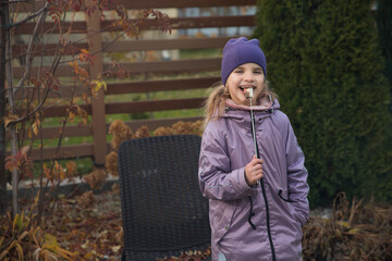 An eight-year-old girl roasts marshmallows on an autumn day near a country house