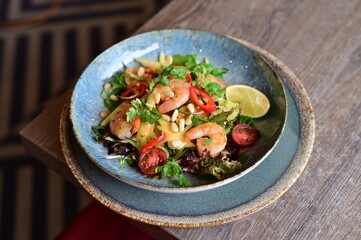 Background view of a gourmet shrimp salad with vegetables and mango, elegantly served on a table in...