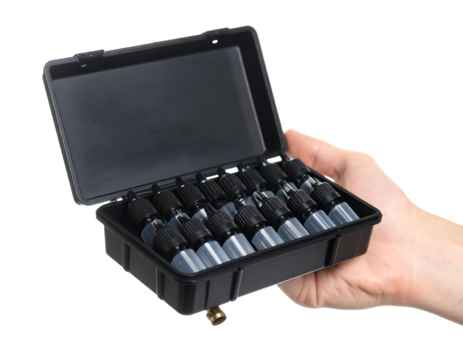 Hand holding a black plastic container with small, dark gray bottles inside.  Transparent background