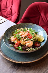 Spicy salad with prawns and shrimps on wooden table
