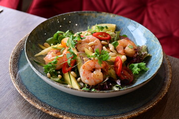 Spicy salad with prawns and shrimps on wooden table