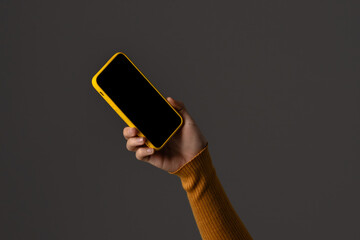 Hand Holding Yellow Smartphone on Dark Background Image