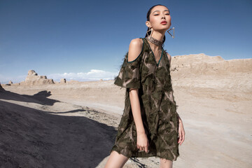 Stylish female model in a textured dress on a desert landscape.