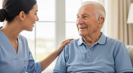 Fototapeta premium Caring nurse comforting a happy senior man with a hearing aid in a retirement home.