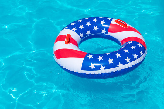 American Flag pool float. Top view of ring circle on blue water background. Summer vacation concept. Vacation in USA concept. 4th of July pool party. High quality photo