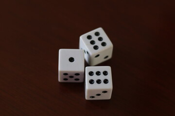 Una toma de cerca  de uno o varios dados blancos para juego en una mesa de color marrón oscuro como fondo