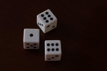 Una toma de cerca  de uno o varios dados blancos para juego en una mesa de color marrón oscuro como fondo