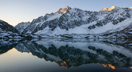 Majestic Mountain Peaks Reflected in a Serene Winter Lake at Dawn